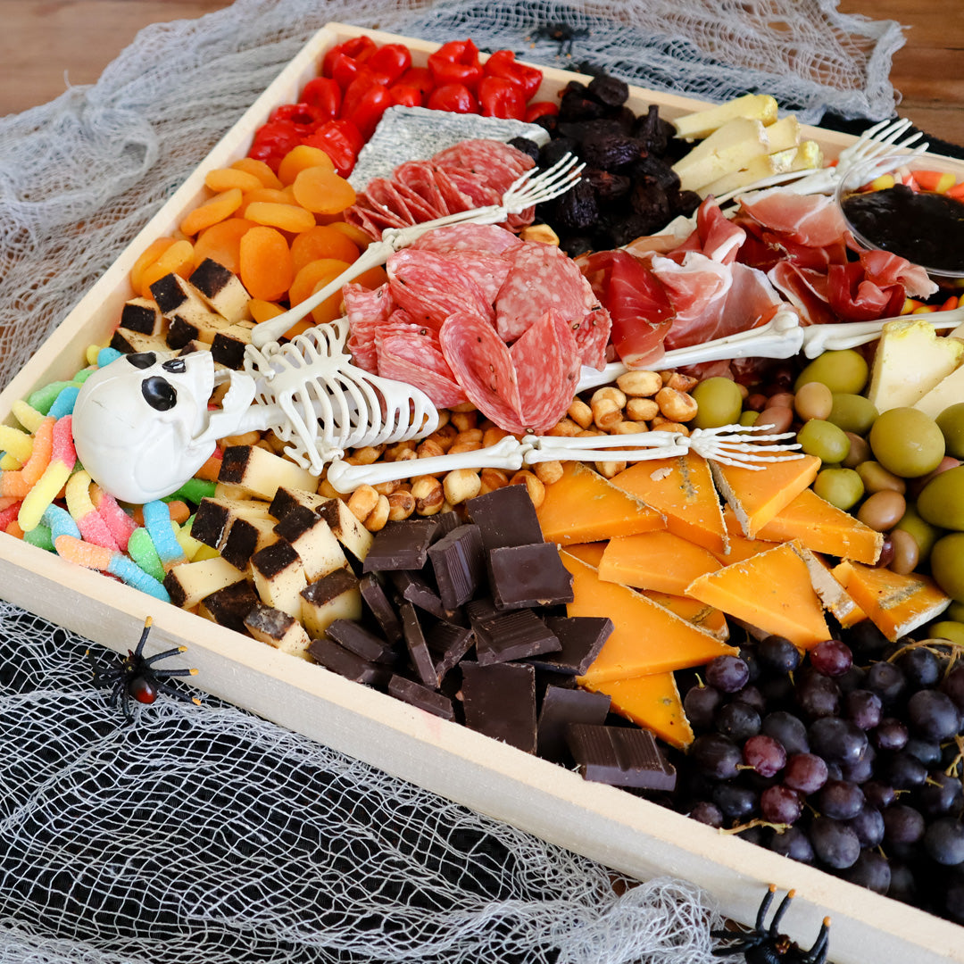 cheese board with a skeleton and Halloween candy on it