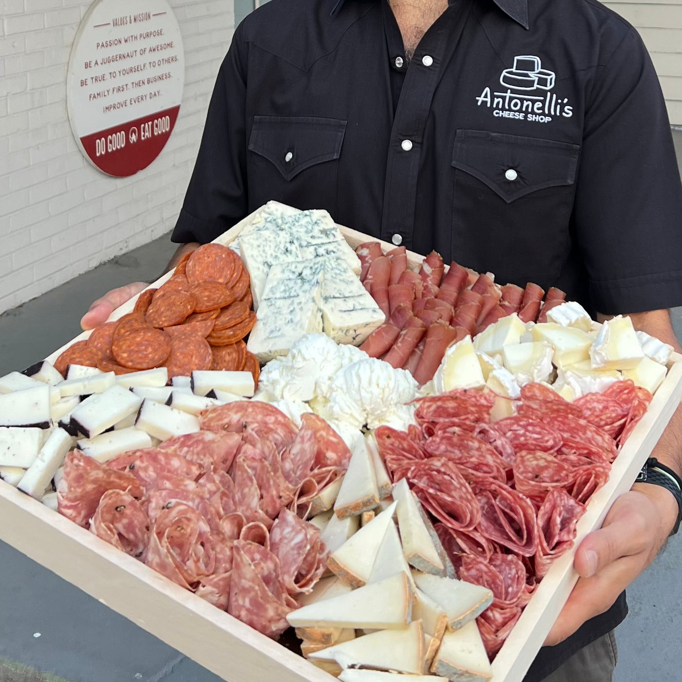 cheesemonger holding a large cheese and meat tray