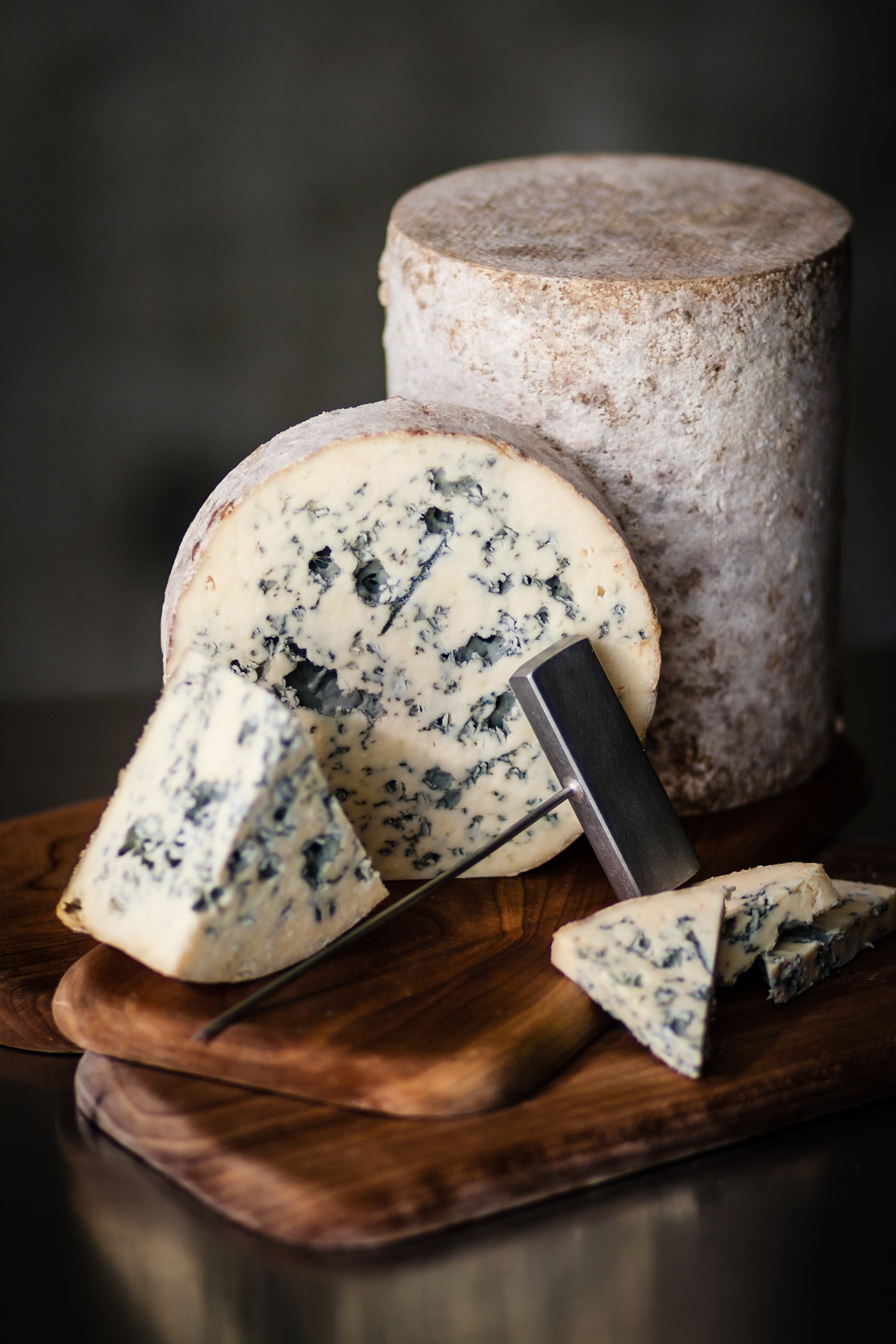 Blue cheese on a wooden board with a cheese knife, showcasing texture and marbling.