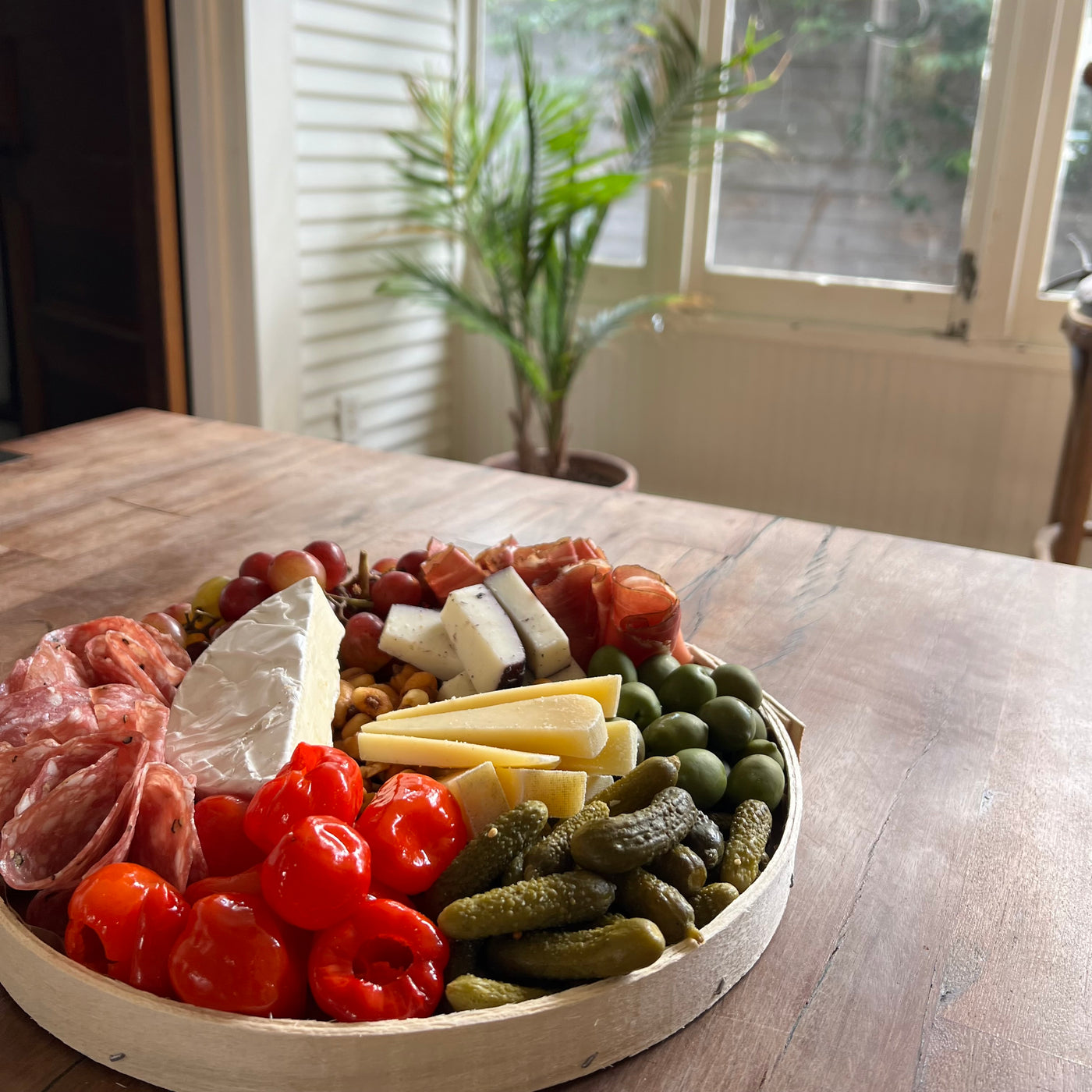 IMage of cheese board for two on a picnic table with windows in the background