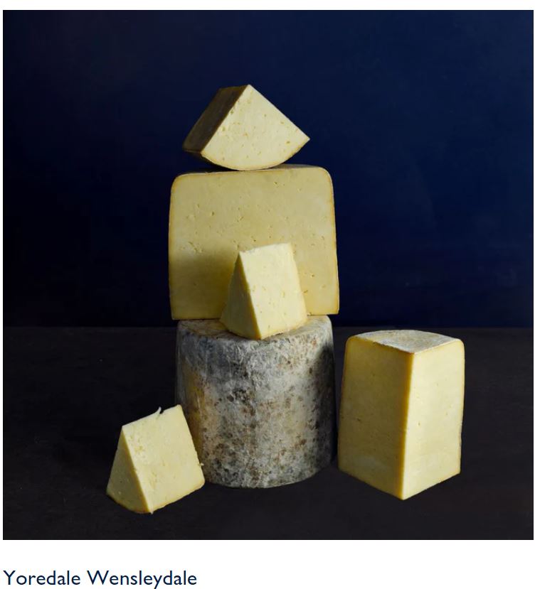 Assorted blocks of Yoredale Wensleydale cheese arranged artistically against a dark background.